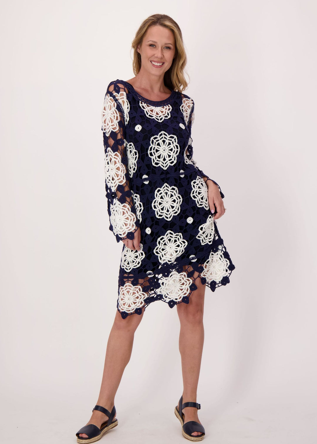 Woman wearing a navy dress with white floral pattern on a plain background