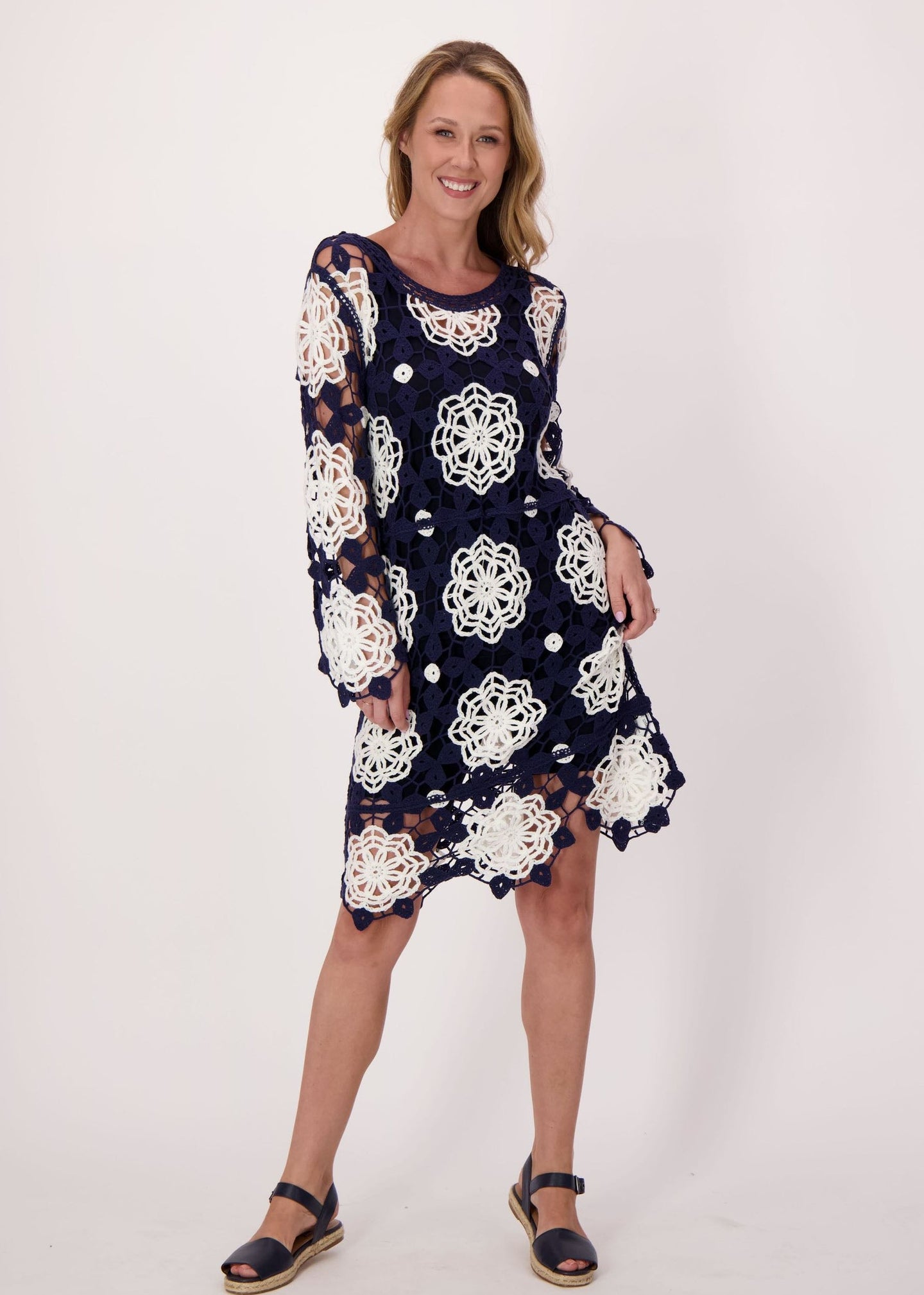 Woman wearing a navy dress with white floral pattern on a plain background
