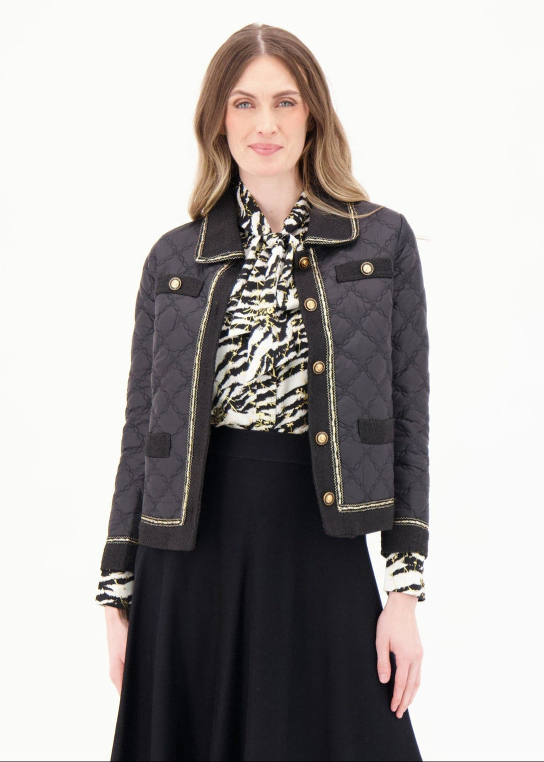 Woman wearing a black jacket, patterned shirt, and black skirt on a white background