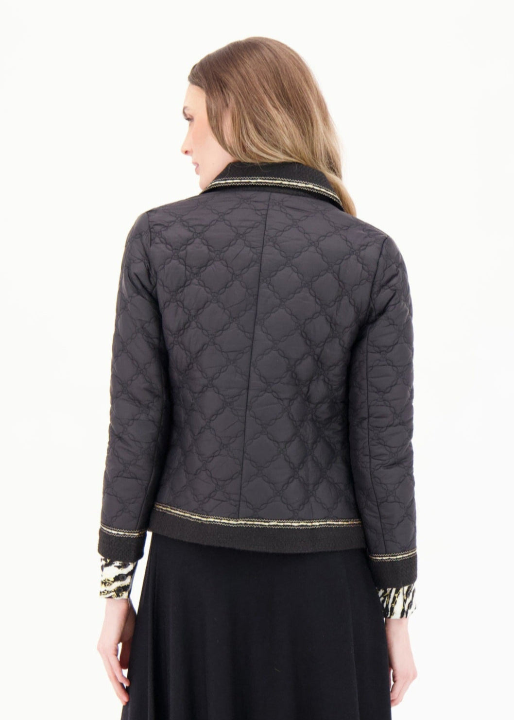 Woman wearing a quilted jacket and black skirt on a white background