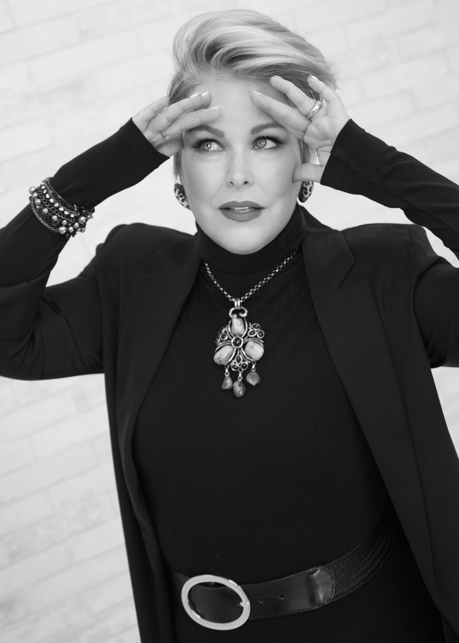 Black and white portrait of a person wearing a black outfit with jewelry.