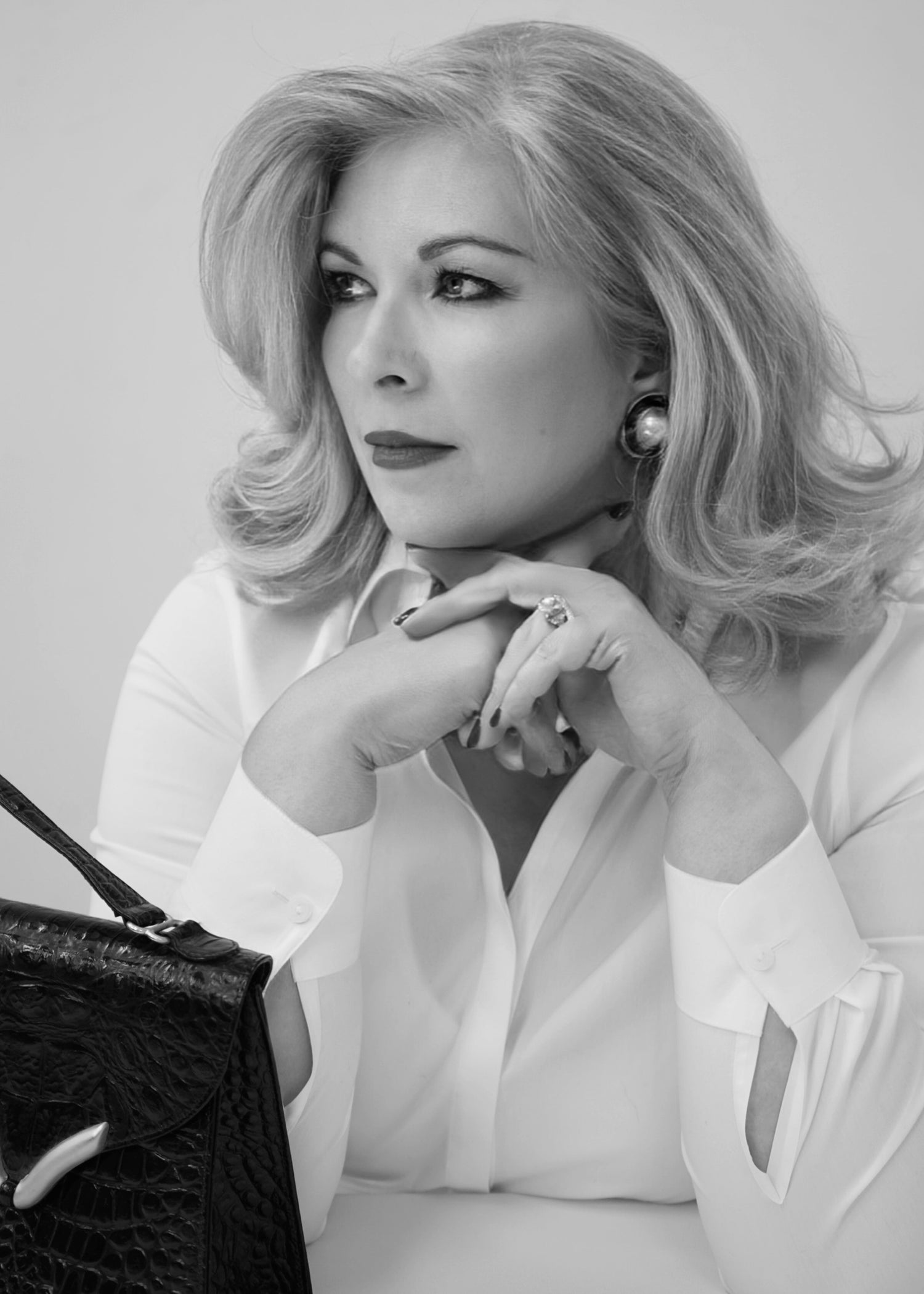 Black and white portrait of a woman with a handbag on a plain background